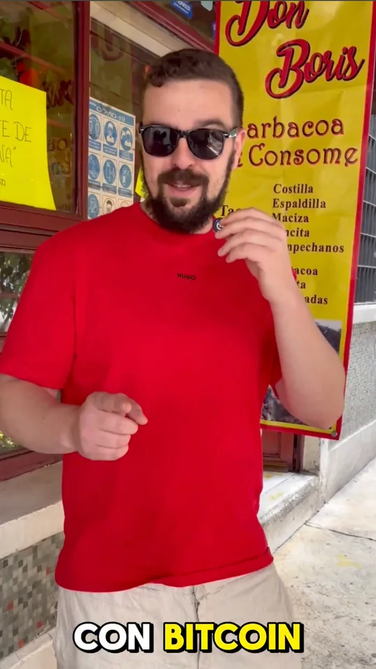A man in a red T-shirt and sunglasses in front of a barbacoa stand, captioned with Bitcoin